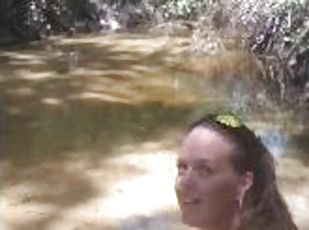 Cute long hair girl on her knees looking for shells to collect in popular spring creek